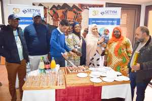 Les participants en train de séparer les parts du gâteau du fêté.